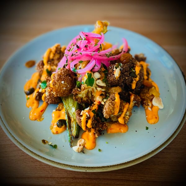 Fried cauliflower and green beans drizzled with orange sauce and topped with pickled red onions.