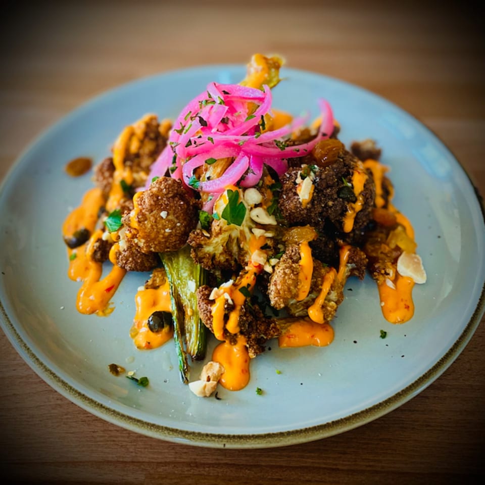 Fried cauliflower and green beans drizzled with orange sauce and topped with pickled red onions.