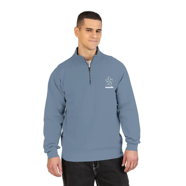 Man wearing a blue quarter-zip sweatshirt with the white Pomelia logo and flower design.