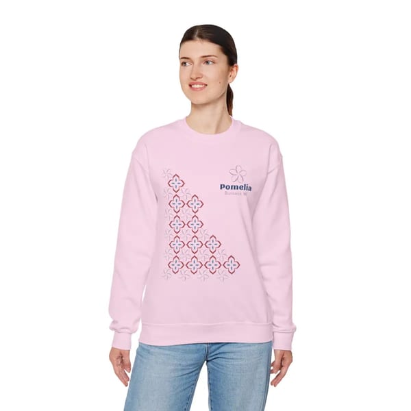 Woman wearing a pink Pomelia branded sweatshirt with a floral pattern and blue jeans.