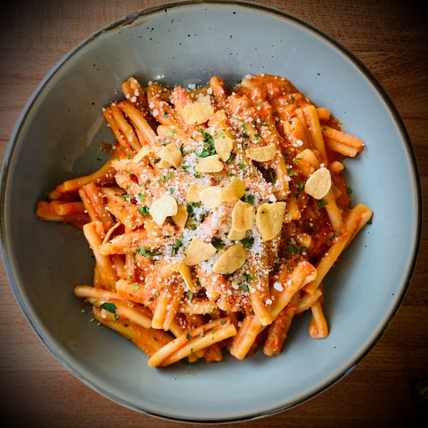 A close-up of Pomelia's Italian pasta dish, topped with red sauce, cheese, parsley, and garlic chips.